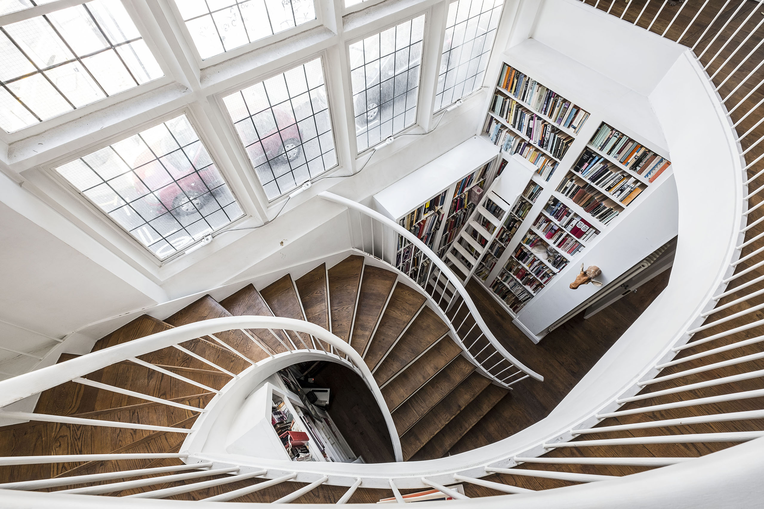 A wooden staircase leading down to a library alcove in loft apartment
